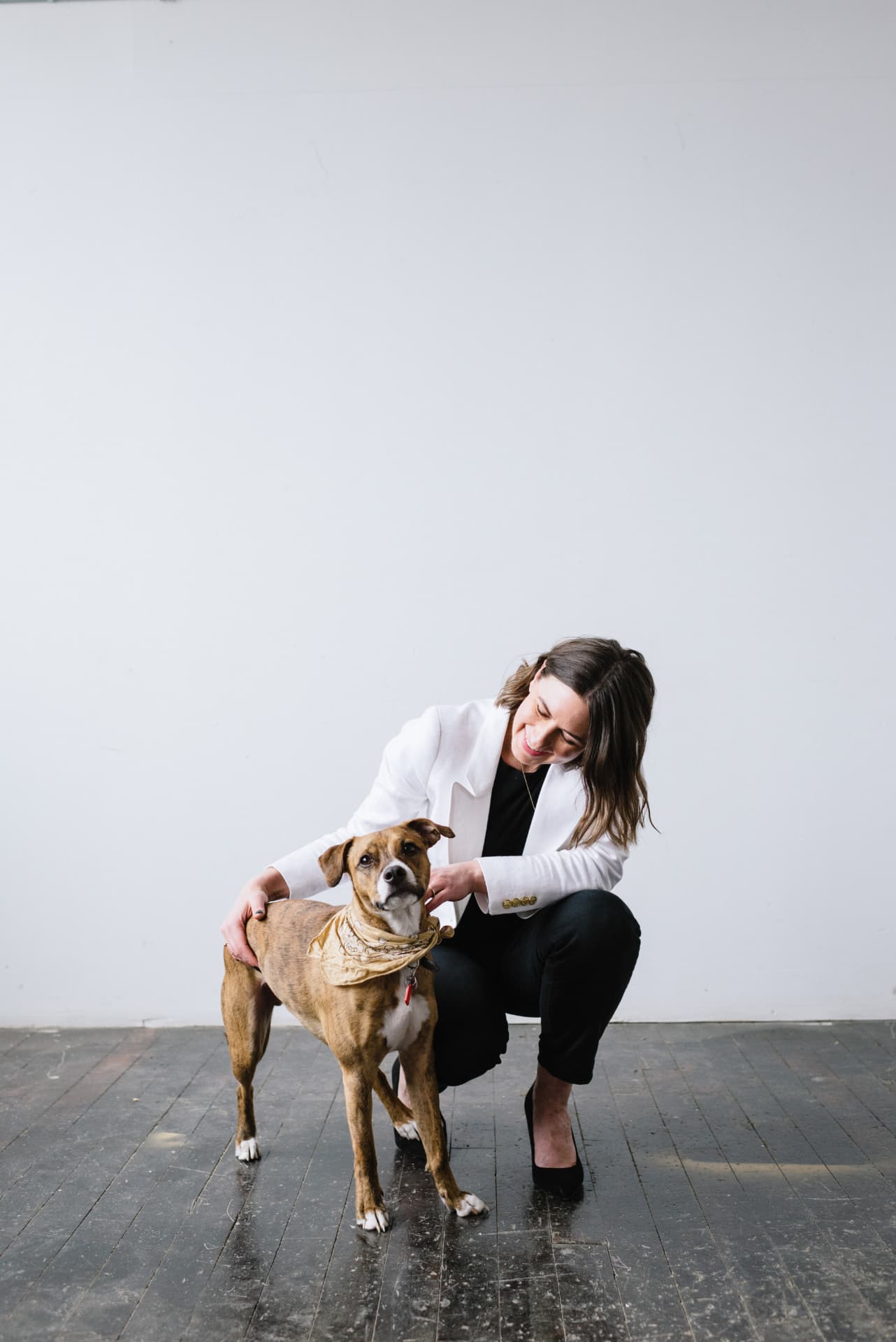 Stephanie kneeling beside her dog Churro in a bright studio space